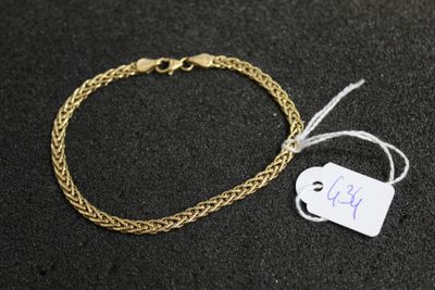 a gold chain bracelet with a tag on a black surface