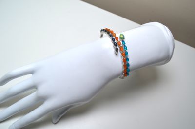 two bracelets on a mannequin hand on a white table