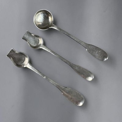 three spoons and a spoon rest on a gray surface