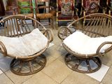 pair of rattan chairs with white cushions in a store