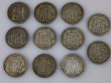 six types différents de pièces d'argent sur une surface blanche