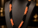 an orange and black beaded necklace on a black mannequin