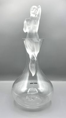 un vase en verre contenant une statuette, posé sur une table