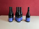 three bottles of wine sit on a table in front of a red wall