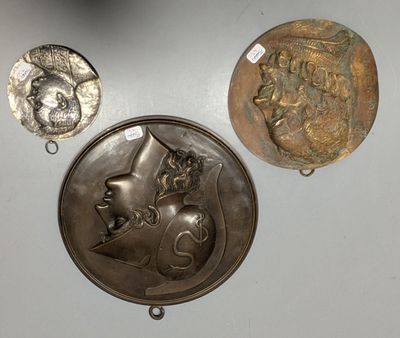 three metal medallions and a coin on a white surface