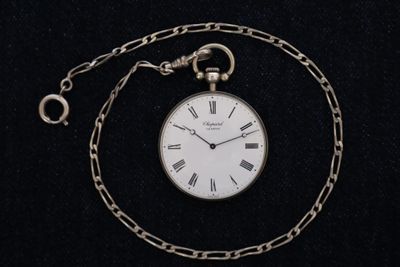 a silver pocket watch with roman numerals on it