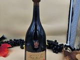 une bouteille de vin posée sur un comptoir, à côté d'une grappe de raisin