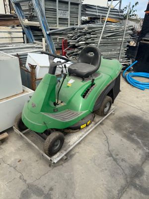 une tondeuse à gazon verte posée sur un chariot dans un jardin