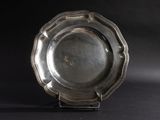 a silver plate on a stand on a black background