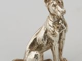a silver figurine of a dog sitting on its hind legs