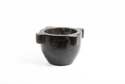une tasse en marbre noir munie d'une anse, sur fond blanc