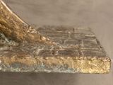 a bronze statue of a bird sitting on a bench