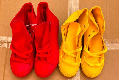two pairs of red and yellow shoes sitting on top of a cardboard box