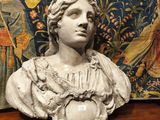 un buste de femme posé sur une table, à côté d'une tapisserie