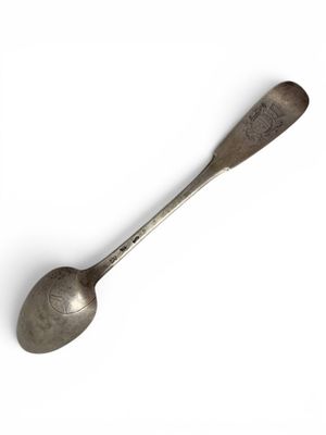 an old spoon with a metal handle sitting on top of a white surface