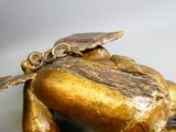 a gold statue of a frog with a leaf on its back