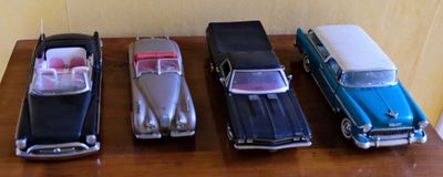 Plusieurs petites voitures sont alignées sur une table devant un mur.