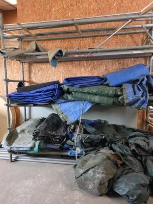 de nombreux sacs de vêtements posés sur un portant métallique dans une pièce