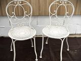 une paire de chaises de jardin blanches en fer forgé posées sur un tapis noir