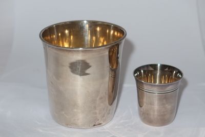 a silver cup next to a silver cup on a table