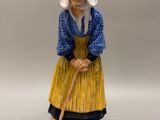 une vieille figurine représentant une femme avec un chapeau et une canne