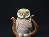une figurine de chouette perchée sur une branche d'arbre
