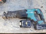 a corded drill and two batteries on a table