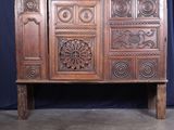 une grande armoire en bois dont la façade est ornée de sculptures