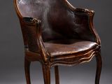 un fauteuil en cuir marron posé sur un sol gris