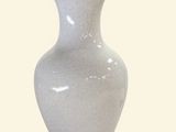 un vase blanc avec un socle noir posé sur une table