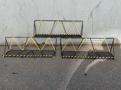 three black and yellow metal racks on the ground