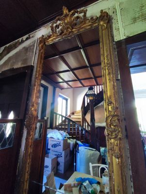 un miroir au milieu d'une pièce, avec un escalier en arrière-plan