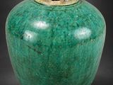 un vase vert posé sur une surface noire