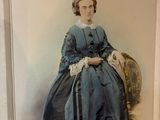 une vieille photo d'une femme en robe bleue, assise sur une chaise