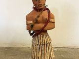 a wooden statue of a man in a skirt and hat