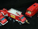quatre camions de pompiers miniatures alignés sur une surface noire