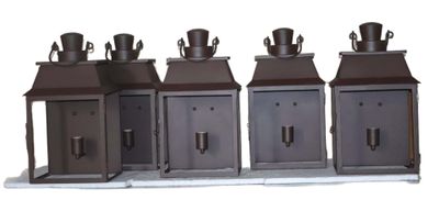 three metal lanterns with hats on top of them on a white surface