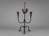 an iron candelab with two candles and a bird on it