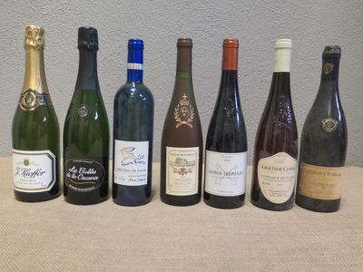 plusieurs bouteilles de vin alignées sur une table, avec un mur en arrière-plan