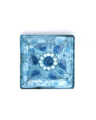 a blue and white tile with a flower design on it