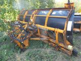 a tractor that is sitting in the grass with a plow attached to it