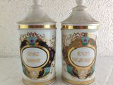 two white and gold canisters sitting on top of a white table