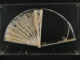 an old fan in a glass case on a black surface