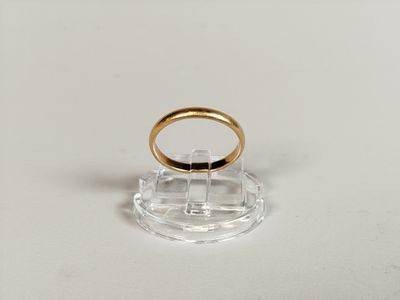 an image of a gold wedding ring on a clear stand