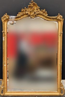 un miroir au cadre doré ouvragé, avec un mur rouge en arrière-plan