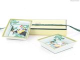 two small square dishes with birds painted on them in a gift box