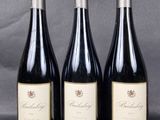 three bottles of wine are lined up on a table