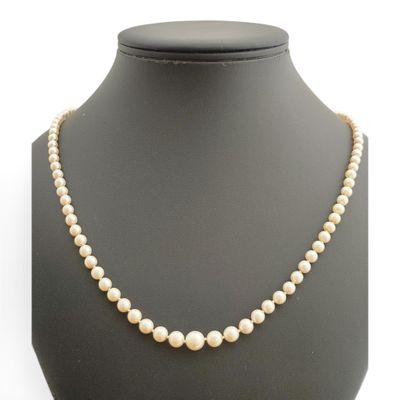 un collier de perles blanches sur un mannequin avec un fermoir en or