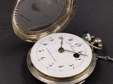 a silver pocket watch sitting on top of a black table