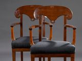 deux chaises en bois aux assises rembourrées noires, sur fond gris